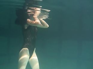 Slim raven-haired cutie undresses while diving inside of a pool
